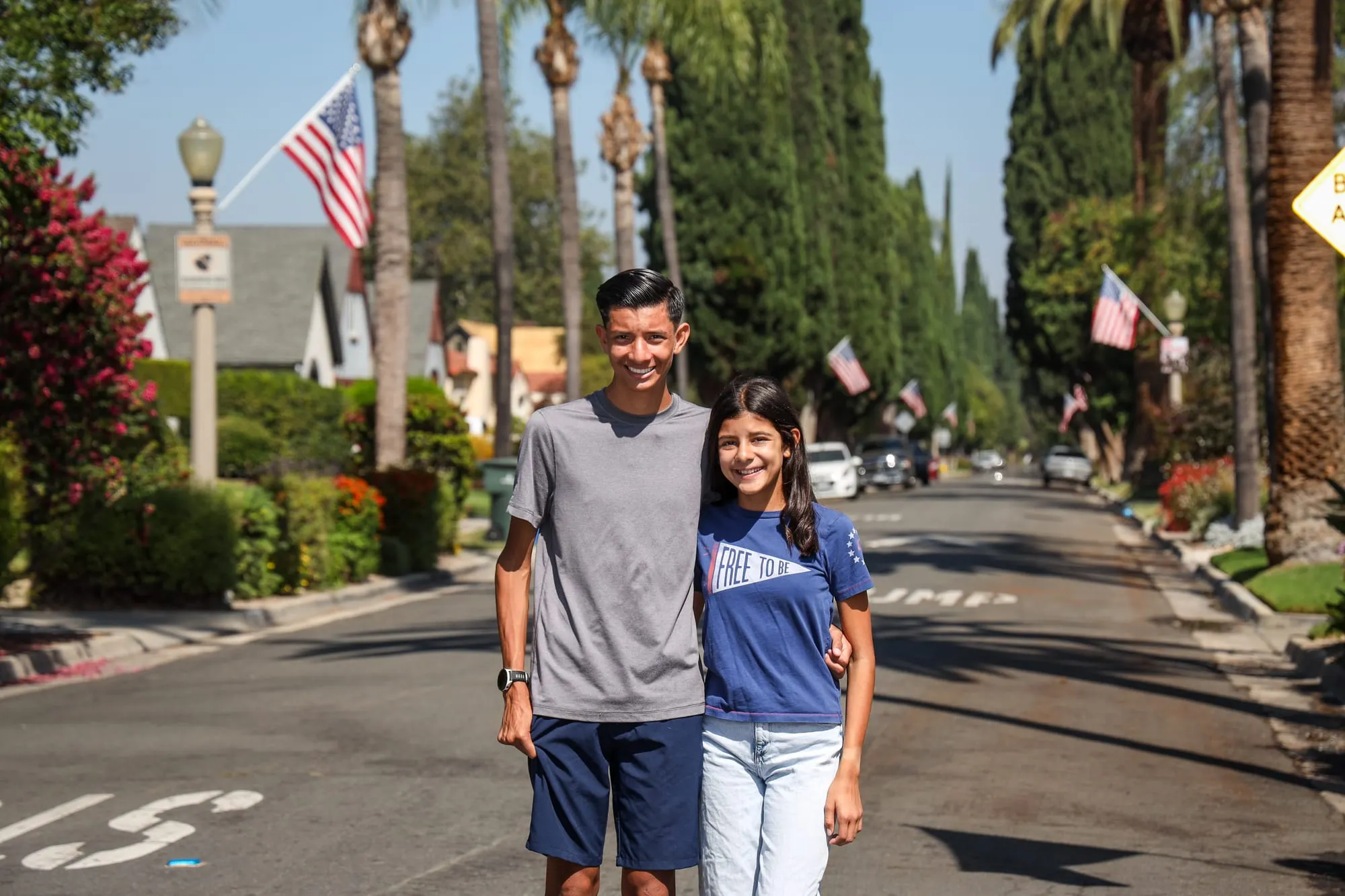 Andrew and Samantha Melendrez standing on a flag-lined street in the Wood Streets neighborhood